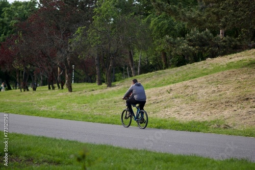 Young adult cyclist leisurely riding a bicycle down a rural road surrounded by trees photo