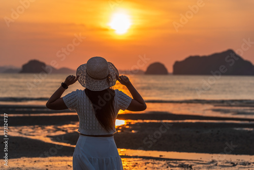 Happy woman traveler, arms rised, enjoying sunset at sea, Phuket and Krabi travel sounthern Thailand. photo