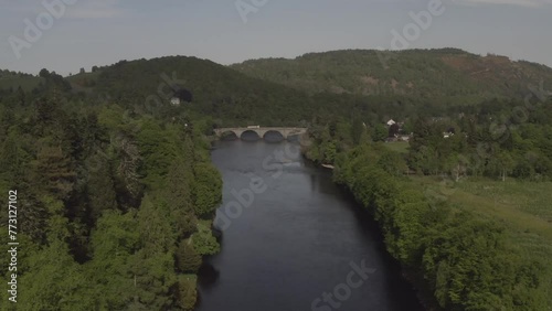 Aerial flying towards Dunkeld Bridge along River Tay with green hills nature scenery in background Scotland, United Kingdom photo