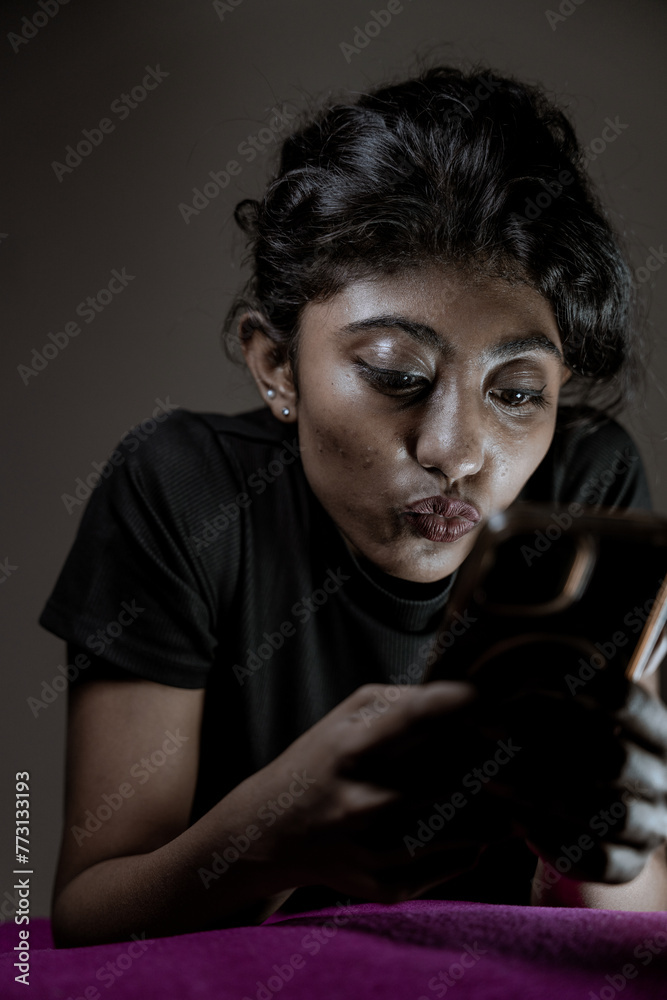 Fototapeta premium A woman is looking at her phone while sitting on a pink blanket