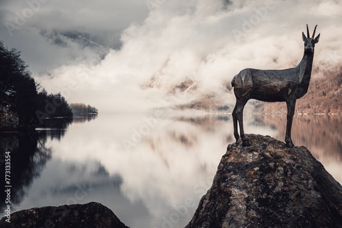 Majestic bronze statue of a deer stands atop a picturesque rock formation