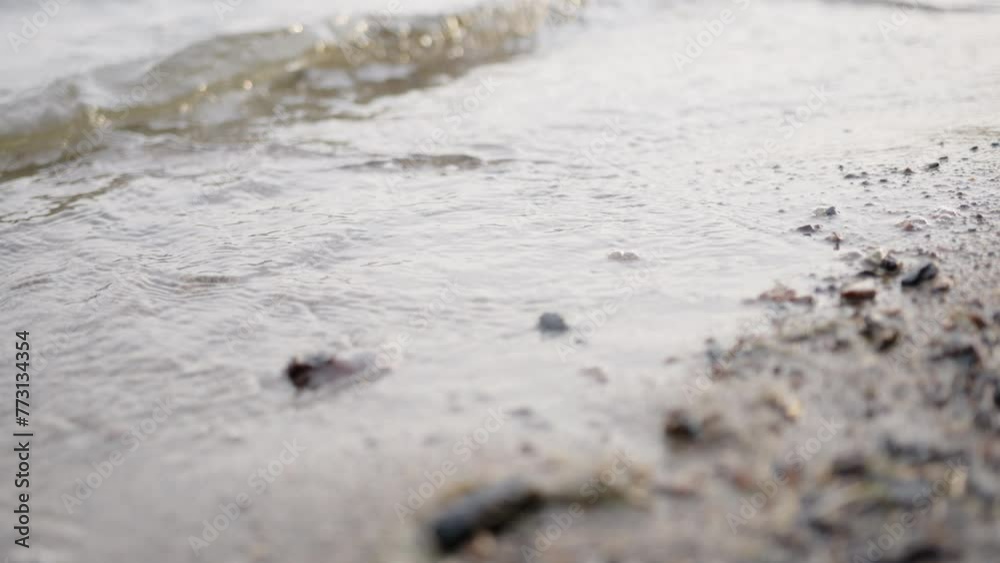 Closeup of the calm waves of the lake hitting the sandy shore Closeup of the calm waves of the lake hitting the sandy shore