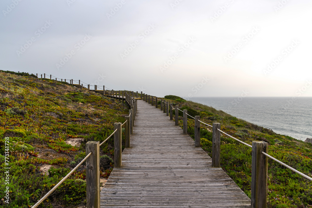 View of nature landscape ocean near Nazare. Wooden walkway to the beach, Portugal. Majestic coastline looking the Atlantic Ocean.