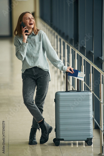 Luggage bag and smartphone. Young woman in airport hall