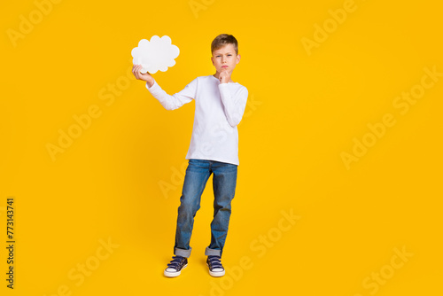 Full length photo of doubtful unsure boy wear white shirt arm chin holding mind bubble empty space isolated yellow color background