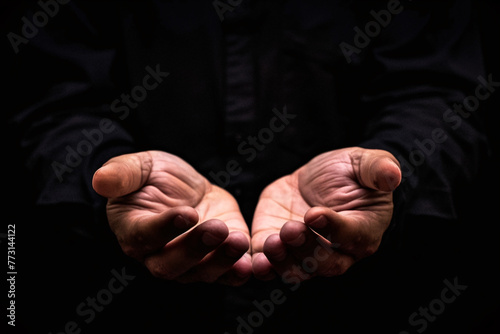 close up of male hands begging or holding something over black background © Di Studio