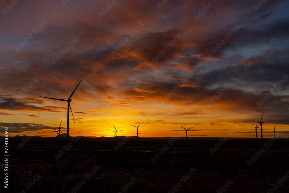 Scenic landscape featuring a line of large wind turbines under a sunset sky Scenic landscape featuring a line of large wind turbines under a sunset sky