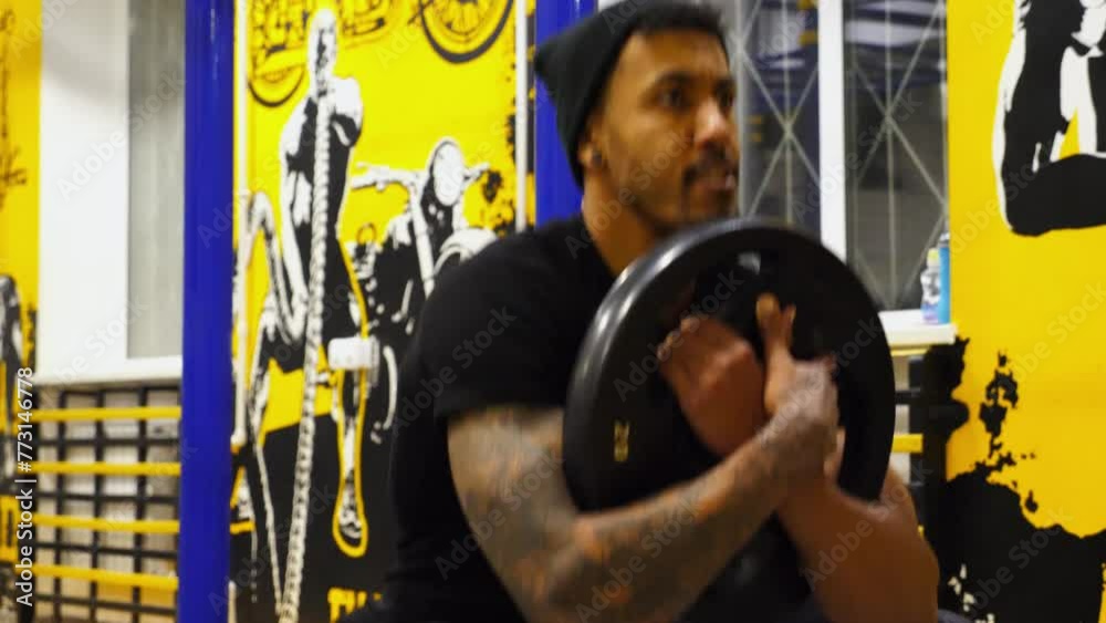 Strong african athlete sit down with weighted plate at sport club ...