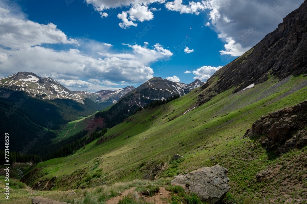Scenic view of a green mountain range under a cloudy blue sky in Colorado Scenic view of a green mountain range under a cloudy blue sky in Colorado