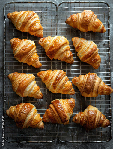 A top-down photo of several freshly baked croissants on a wire rack, Generated by AI
