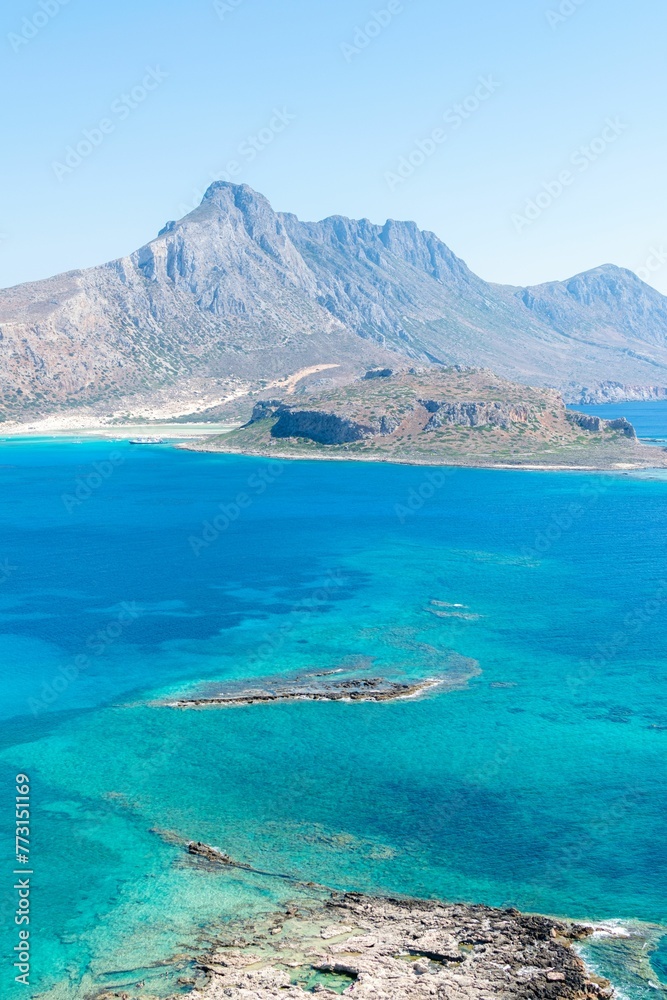 Crystal-clear turquoise waters of Crete island in Greece with a rocky shoreline and hills