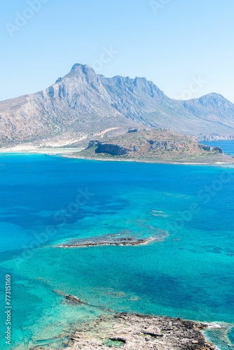 Crystal-clear turquoise waters of Crete island in Greece with a rocky shoreline and hills © Wirestock