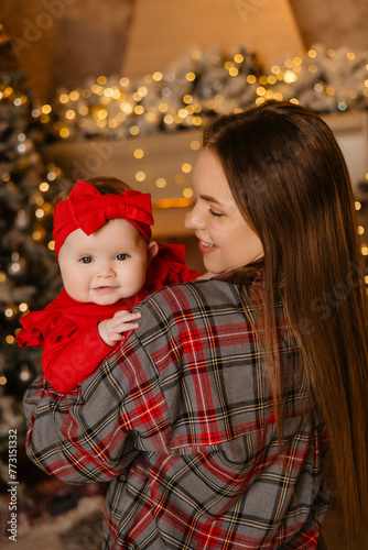 a woman is holding a baby in her arms in front of a christmas tree