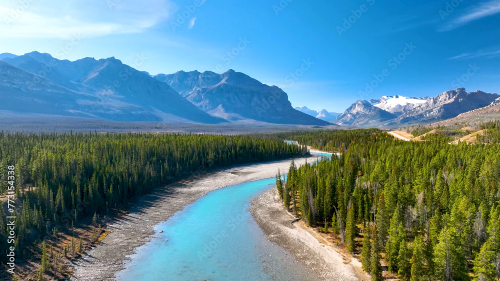 Stunning landscape of a river winding through forest and majestic mountain peaks in the background