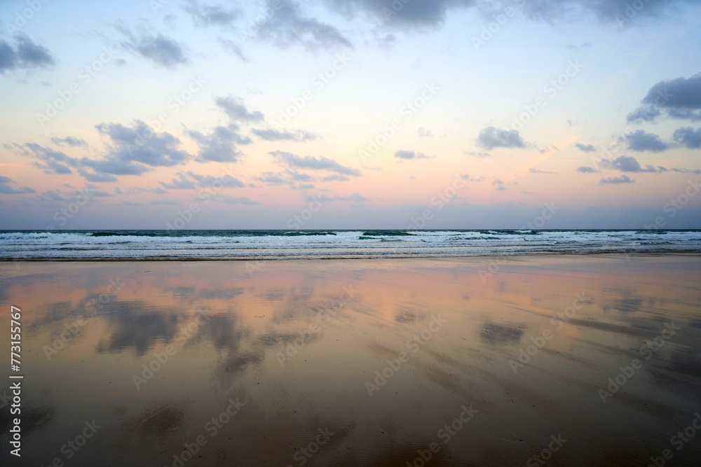 the beach with clouds and sky reflected in it's water