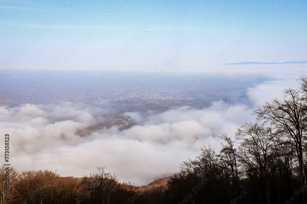 High angle shot of misty clouds from a high place, with a city visible in the background