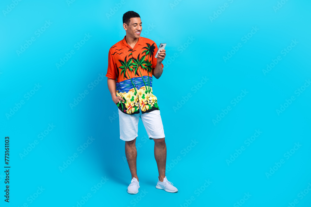 Fototapeta premium Full length photo of cute positive guy dressed print shirt chatting apple iphone samsung modern device isolated blue color background