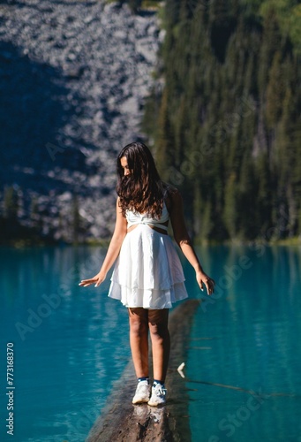 Vertical shot of a young female in a white summer dress standing on the lake surface