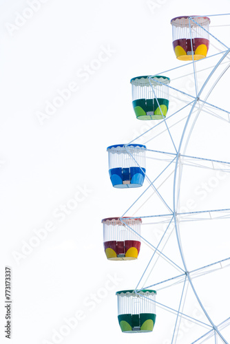 Close up view of a ferris wheel and its colorful cabins on a clear sky