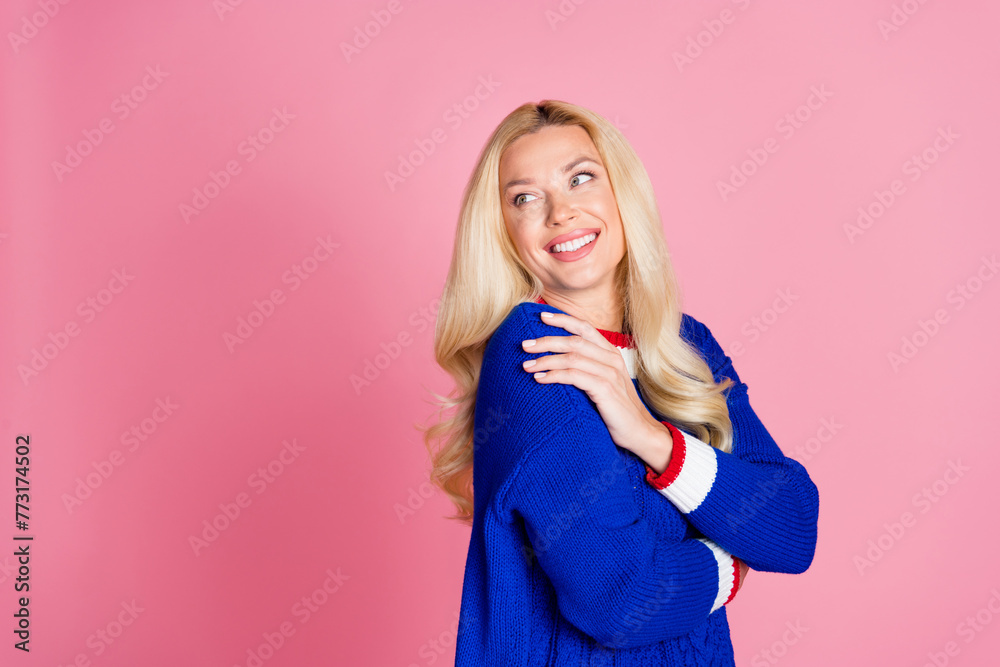Photo of pretty lady hug shoulder look empty space wear blue sweater isolated on pink color background Photo of pretty lady hug shoulder look empty space wear blue sweater isolated on pink color background