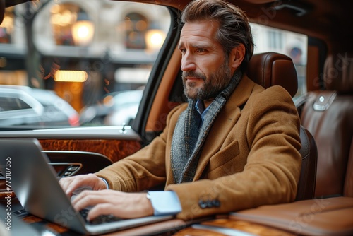 Driving on a highway, the businessman demonstrates the seamless connectivity of luxury car's technology features, effortlessly accessing emails and documents on laptop while en route to destination © arti om