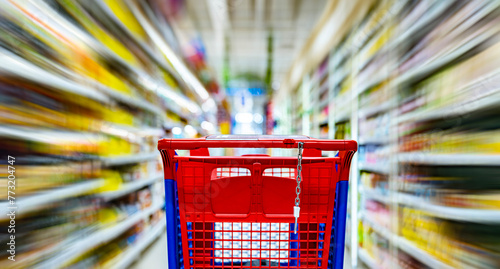 A shopping cart by a store shelf in a supermarket © monticellllo