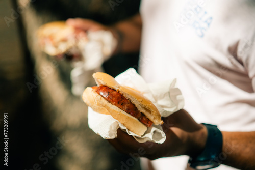 man eating traditional Argentine choripan sandwich at a street food market