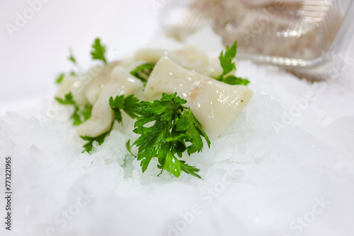 Raw fresh squid with parsley on ice background. Top view.