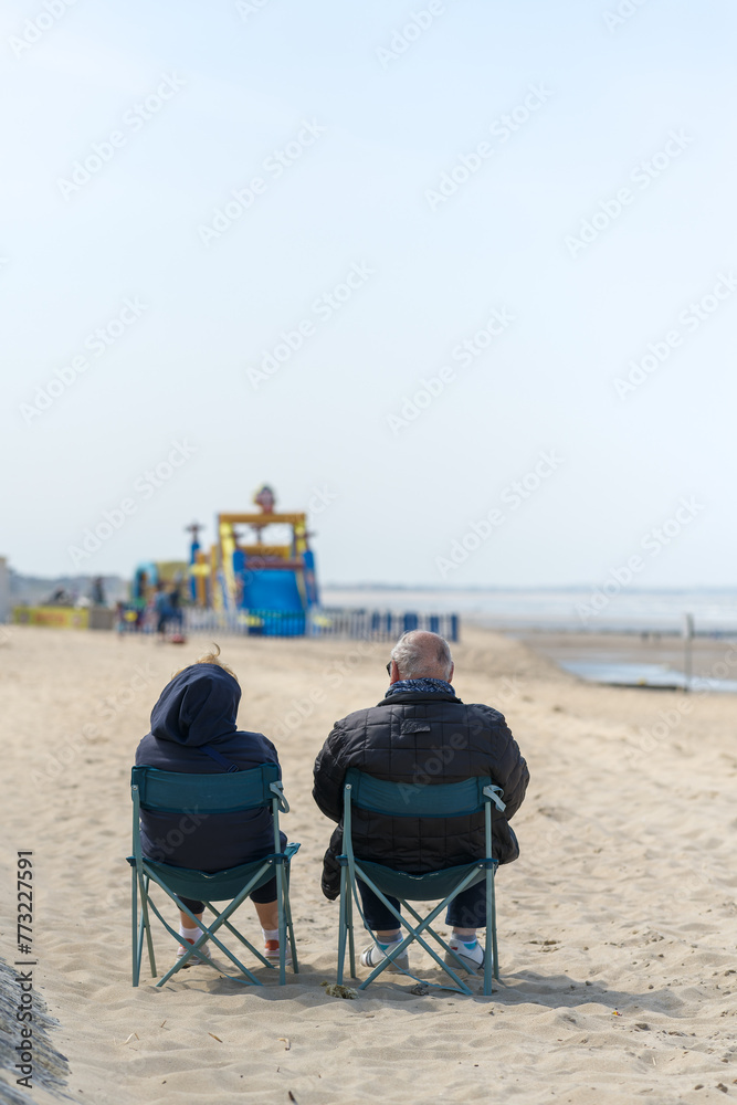 Couple de retraités qui regardent au loin sur la plage de Cabourg à l'automne