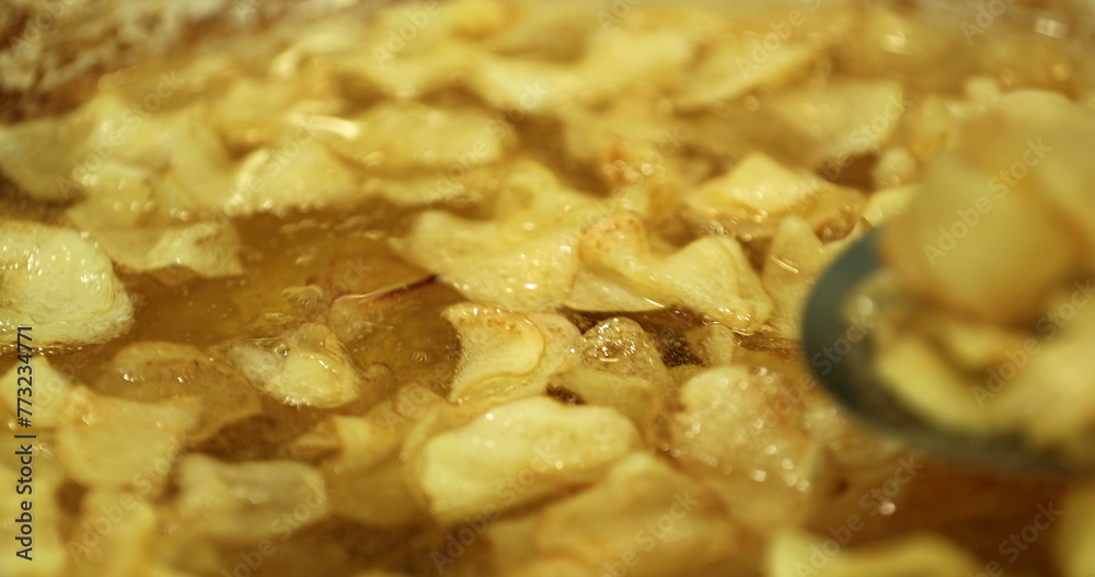 Frying traditional potatoes crisps on large frying pan