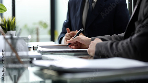 Three men in suits are sitting at a table with a pen and papers