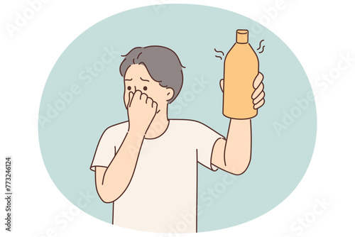 Man covers nose holding bottle of drink or milk that has expired and begun to ferment