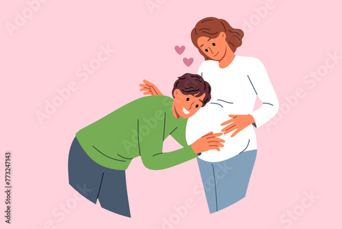 Future dad leans against belly of pregnant woman, listening to movements of baby in womb. Pregnant girl feels love and affection of groom, who is looking forward to birth of child.