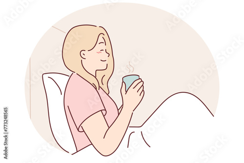 Woman is drinking coffee sitting in bed under blanket enjoying morning weekend and good mood