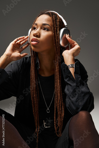 Canvas-taulu african american woman in 20s with dreadlocks enjoying music in trendy headphone