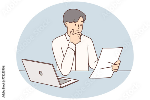 Embarrassed businessman with documents from bank or tax office sitting at table with laptop