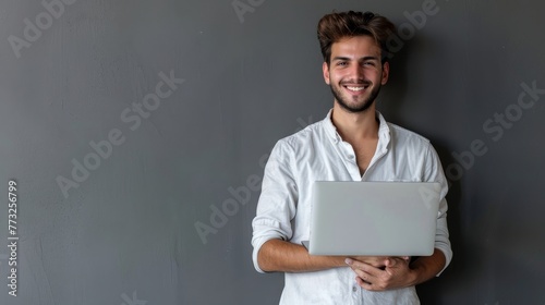 Businessman wearing a light shirt posing isolated on a grey wall background in a studio portrait. Achievement career wealth business concept mock up. Holding a laptop desktop computer. photo