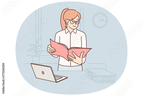 Business woman with documents stands in office near table with laptop checking reports employees
