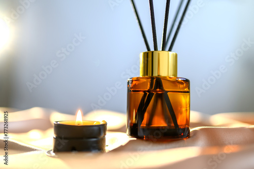 Room freshener with aroma oil and sticks. On the material. With a candle.
