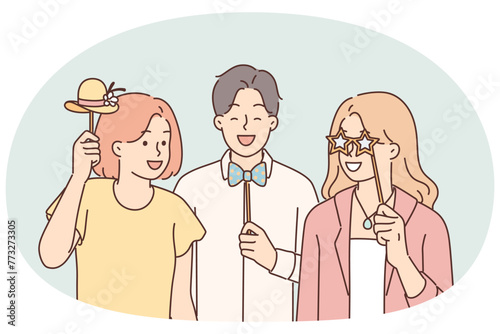 Cheerful friends with photo props pose for joint picture during birthday party or holiday festival
