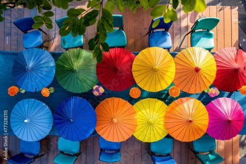 A group of brightly colored umbrellas arranged in a rainbow array on a wooden floor