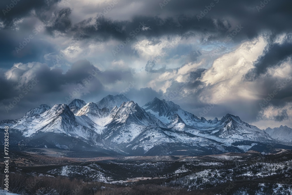 A view of snow-covered mountain peaks under a thick layer of clouds in a mountain range