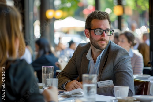 A man is seated at a table inside a restaurant, engaged in conversation with other guests during a speed networking session