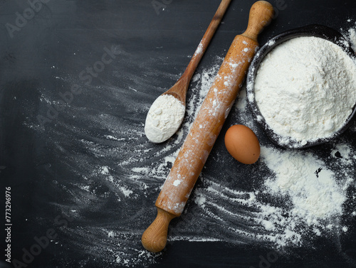 Baking background. Flour and rolling pin on dark table with copy space, top view. World Bread Day photo