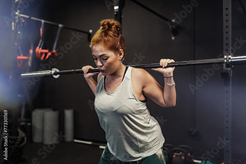 Athletic woman engaging in a strenuous gym workout, showcasing strength and determination, against a backdrop of gym equipment - Strength Training - Athletic Commitment