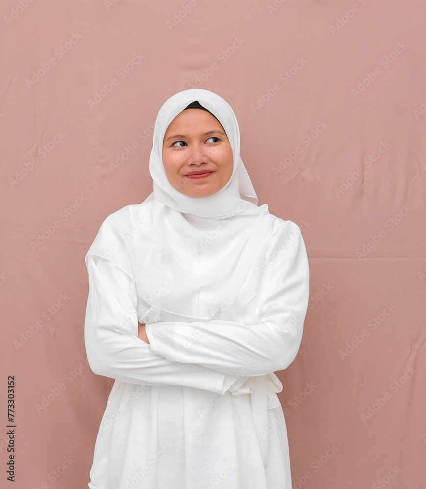 Asian woman wearing a hijab wearing white clothes typical of Eid al-Fitr with a smiling expression and folded hands Asian woman wearing a hijab wearing white clothes typical of Eid al-Fitr with a smiling expression and folded hands