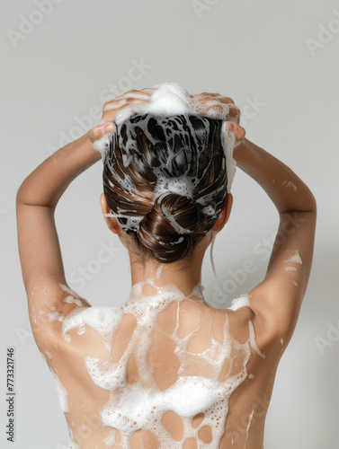 back view of young woman washing wet and foamy hair isolated on grey © romanets_v