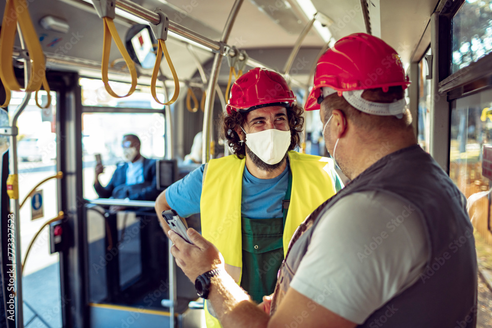 Construction workers with safety helmets and face masks talking on public bus Construction workers with safety helmets and face masks talking on public bus