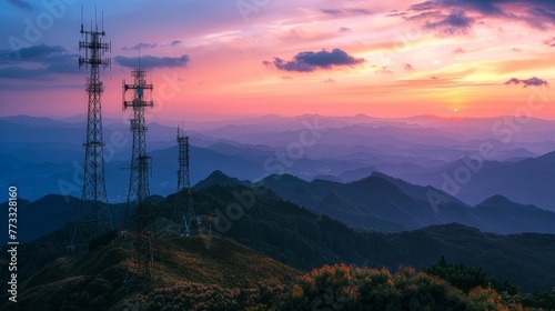 A beautiful sunset over a mountain range with three tall towers in the background. The towers are likely cell phone towers