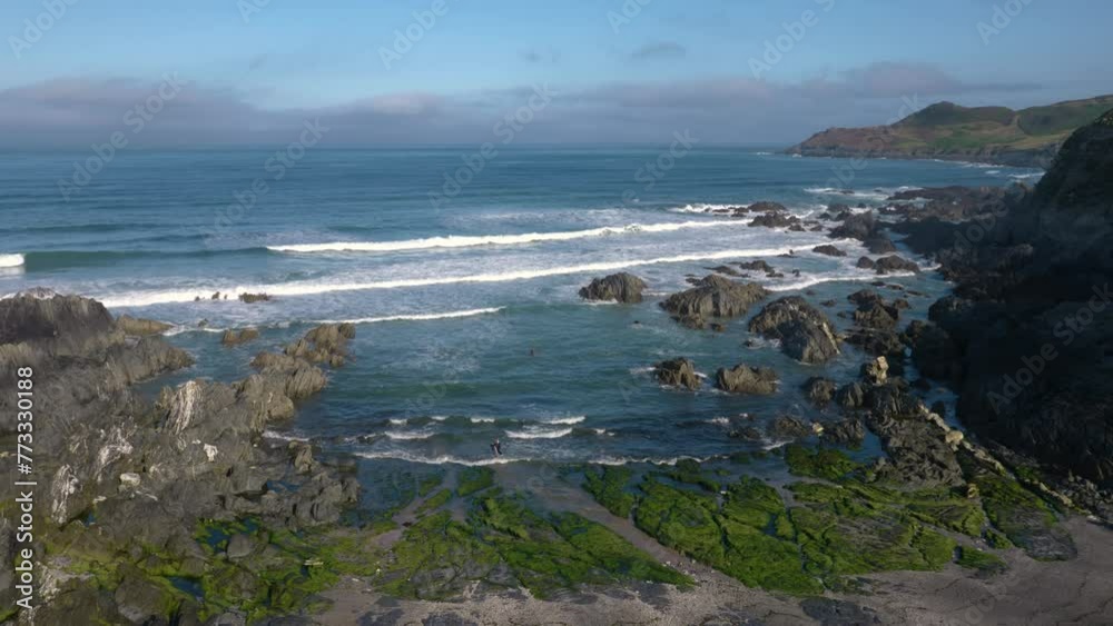 Wide establishing shot of Combesgate Beach during high tide in summer in Woolacombe, Devon, England Wide establishing shot of Combesgate Beach during high tide in summer in Woolacombe, Devon, England